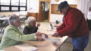 Joyce Hansen hands a ballot to Douglas Rye while Barb Andersen explains proper procedures in voting Tuesday at the Ward 3 polls in United Methodist Church. -- Michelle Haacke/Albert Lea Tribune