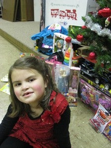 Clara Thompson, 6, of Albert Lea sits with her donation to the Toys for Tots campaign. --Deb Nicklay/Albert Lea Tribune 