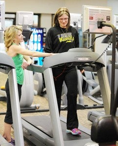 Amanda Schavey, right, talks with Anytime Fitness owner Shawn Bromeland Tuesday during a workout on a treadmill. - Micah Bader/Albert Lea Tribune